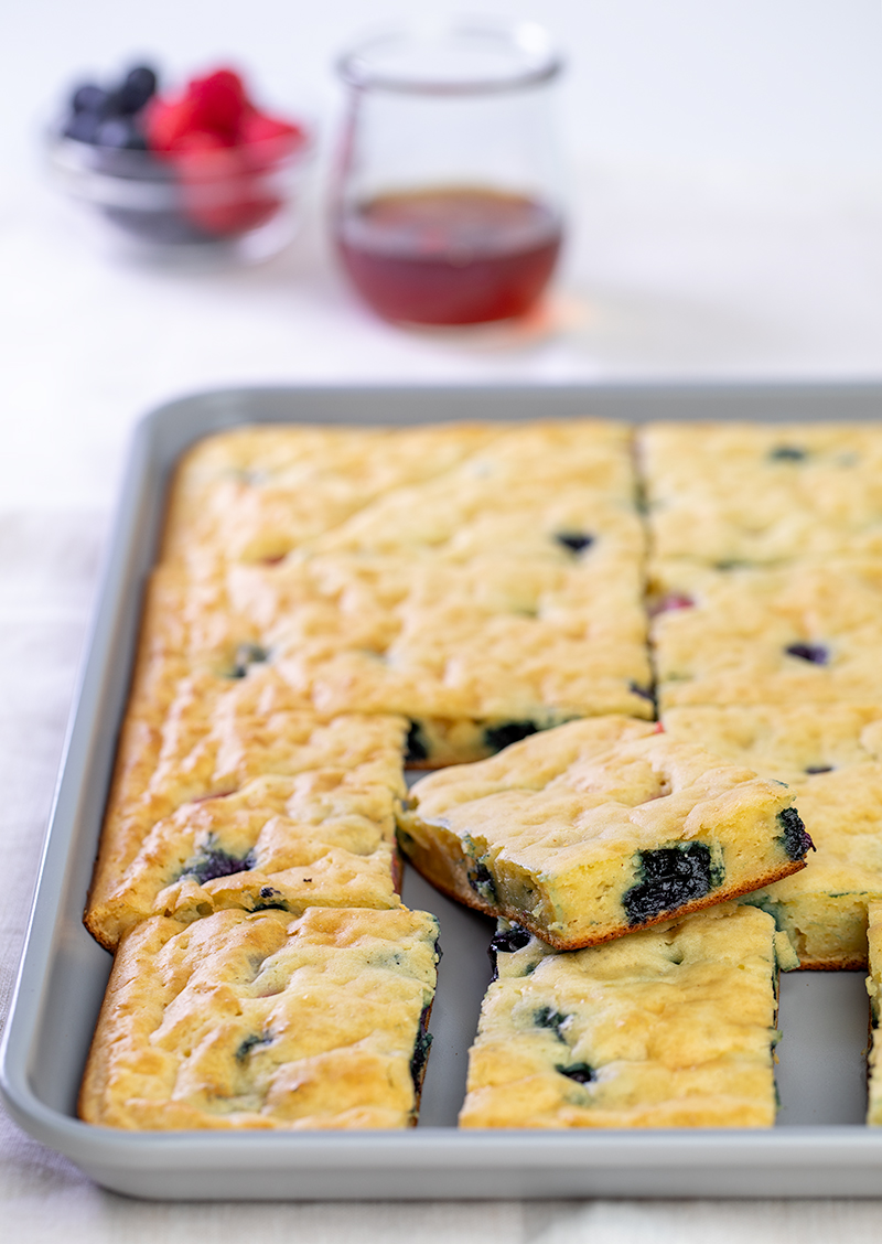 Sheet pan pancakes with blueberries sliced in gray pan