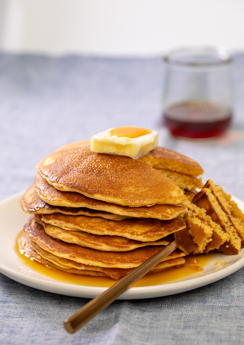 Stack of cornmeal pancakes with forkful of cut pancakes