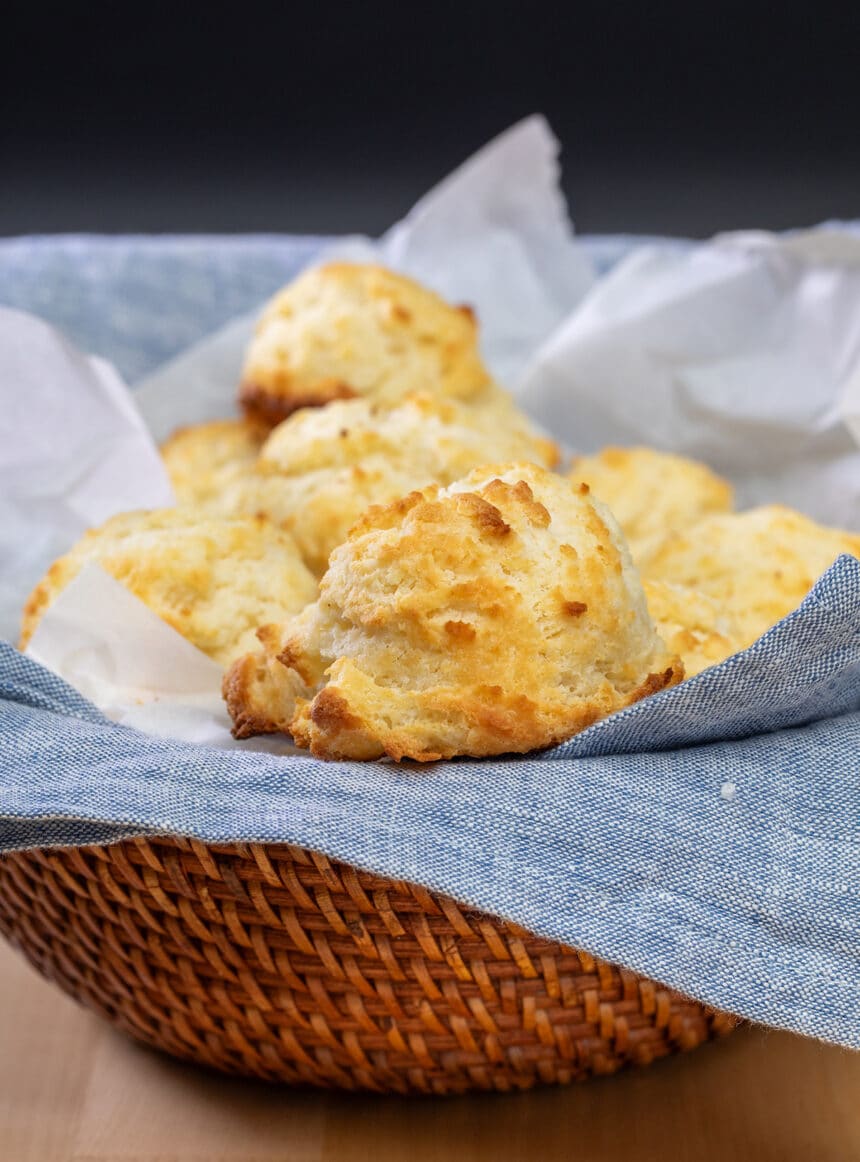 Baked biscuits in brown bowl with blue cloth liner.