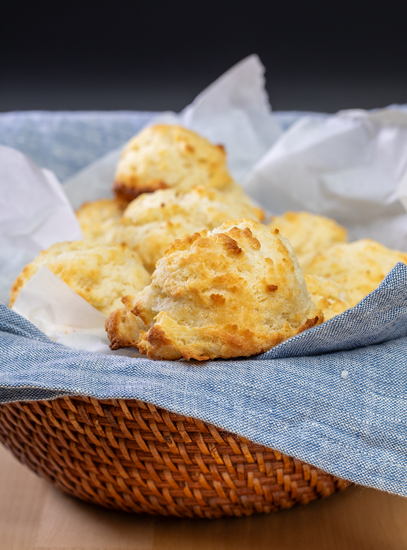 Baked drop gluten free biscuits in brown bowl with blue cloth liner