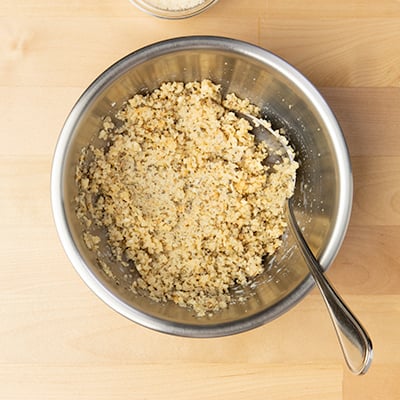 Breadcrumb spice mixture with milk added in small round bowl with mixing spoon