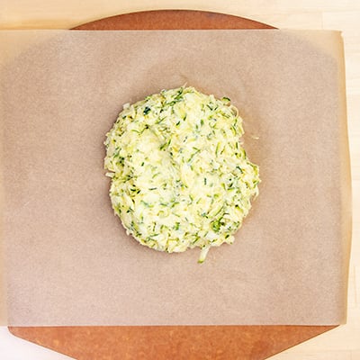 Disk of dough for zucchini pizza on brown parchment paper