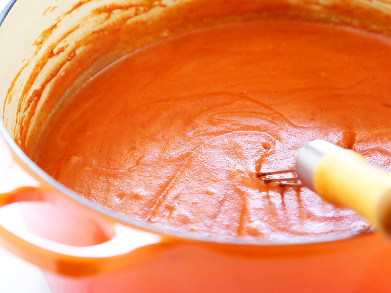 Enchilada sauce in orange pot to make gluten free enchiladas