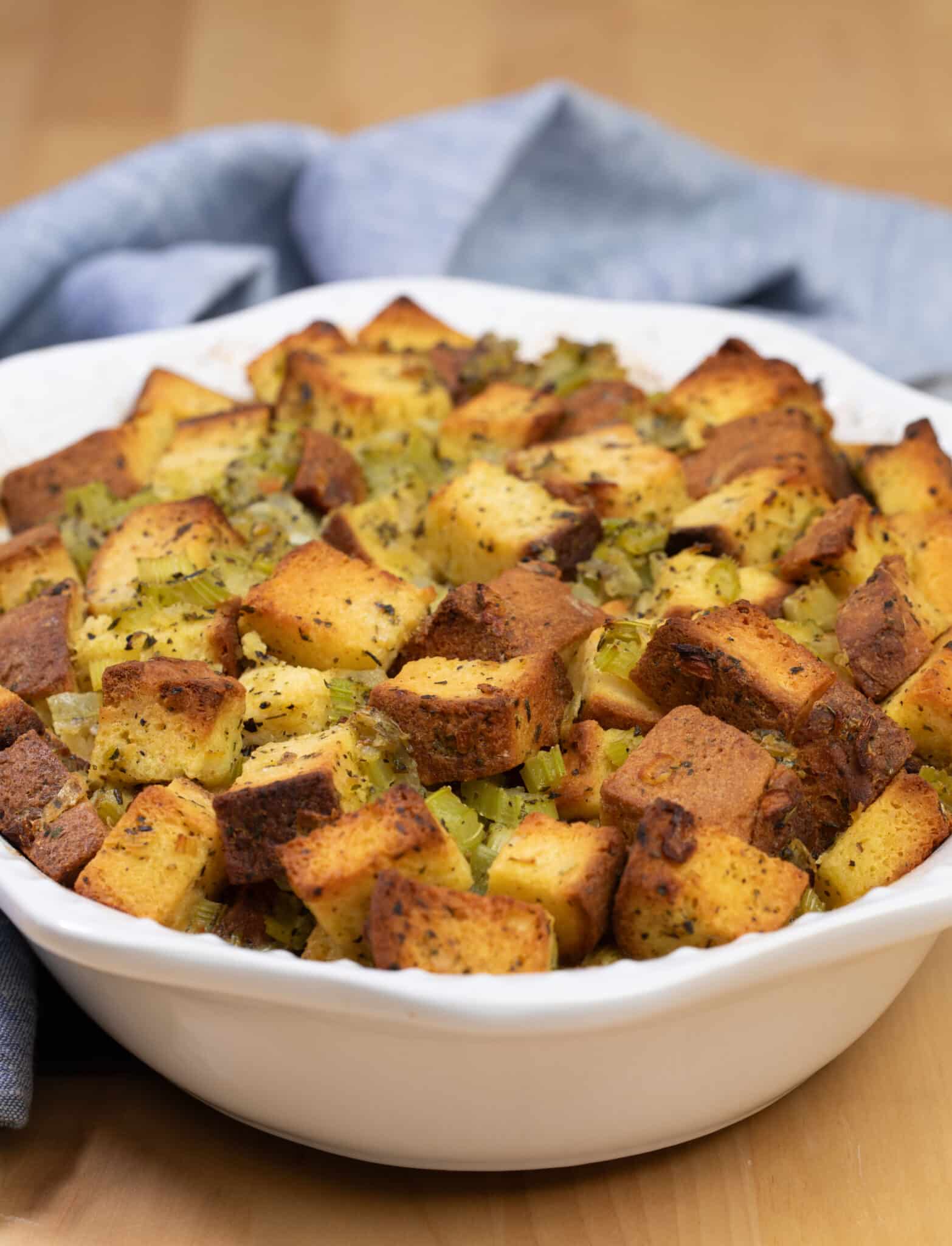 Baked gluten free stuffing in white casserole dish with blue cloth