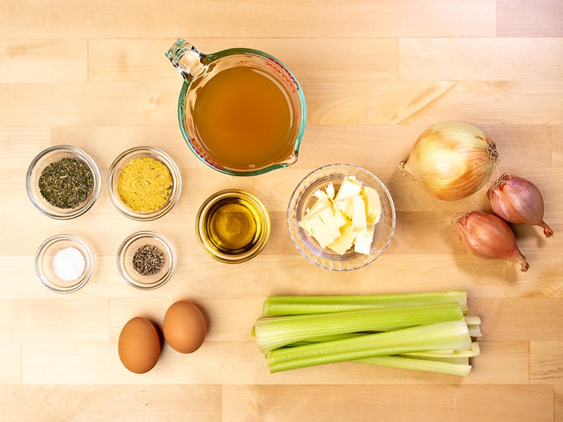 Gluten free stuffing ingredients including bowls of aromatics, spices, herbs, celery, onions, stock and chopped butter