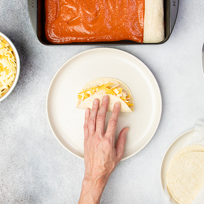 Hand closing corn tortilla with cheese