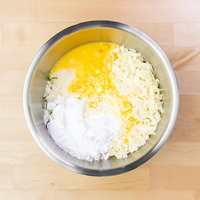 Ingredients for zucchini pizza unmixed in round metal mixing bowl