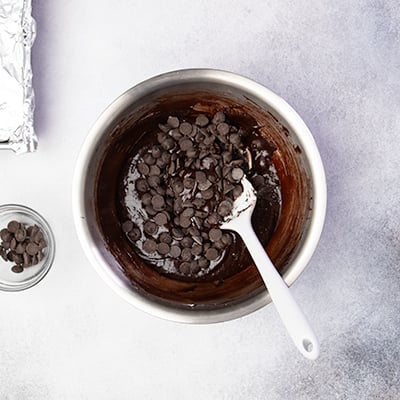 Metal mixing bowl with dark brownie batter with chocolate chips on top