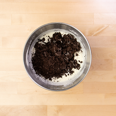 Oreo cookie crumbs in metal mixing bowl