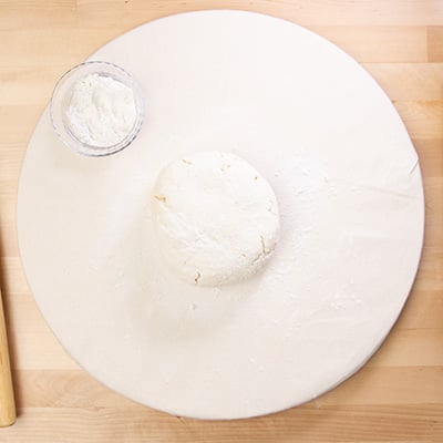 Raw biscuit dough disk on white round cloth