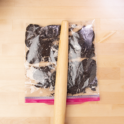 Rolling pin breaking Oreo cookies in ziptop bag