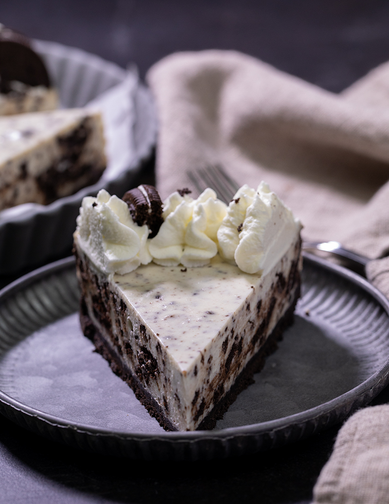 Closeup view of slice of no bake Oreo cheesecake on small gray plate