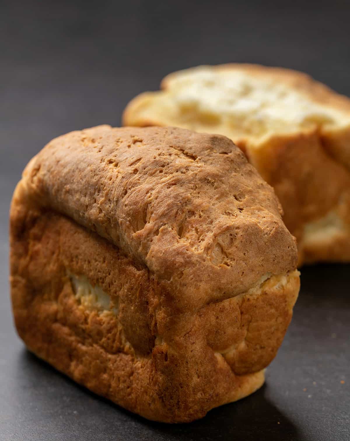Two chunks of gluten free Japanese milk bread on black surface