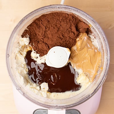 Wet ingredients for protein bars made with peanut butter and chocolate in food processor bowl