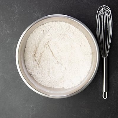 Whisked dry ingredients in round metal mixing bowl with whisk