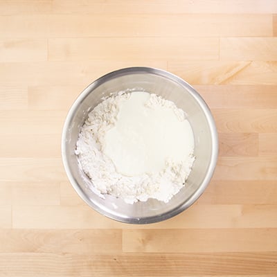 bowl of dry ingredients and butter with unmixed buttermilk on top