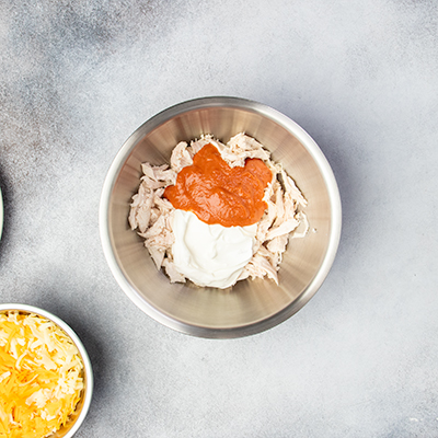 bowl with chicken, red gluten free enchilada sauce and sour cream