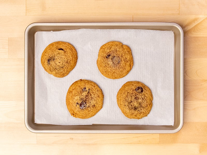 4 baked almond flour chocolate chip cookies on white paper on baking tray