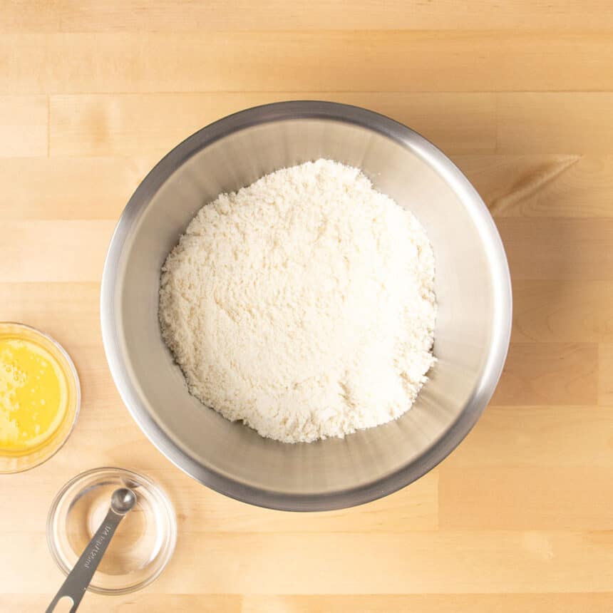 large round metal mixing bowl with pale dry ingredients