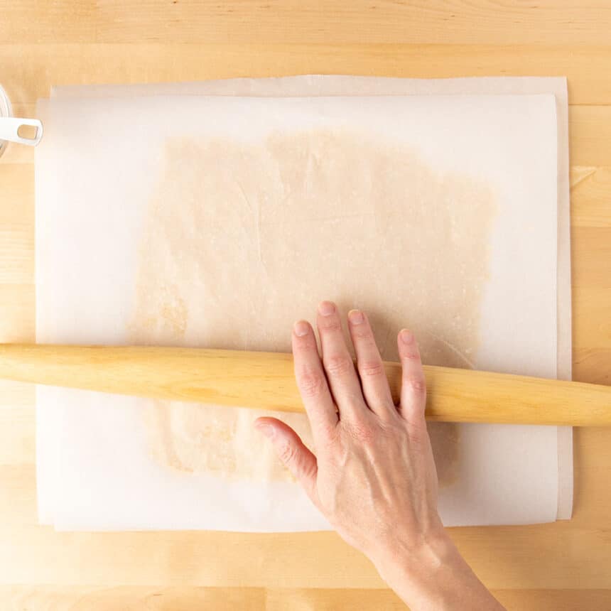 hand rolling wooden rolling pin on top of white paper