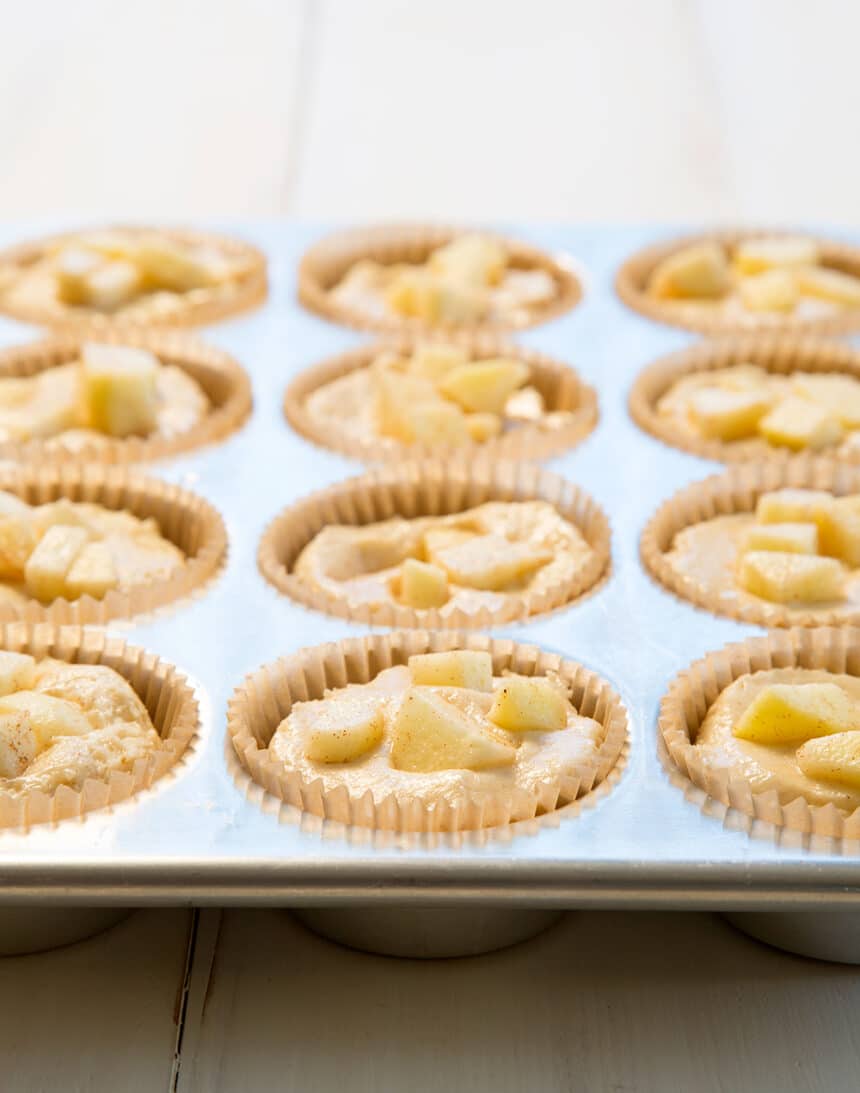 side view of raw apple muffin batter with diced raw apples on top