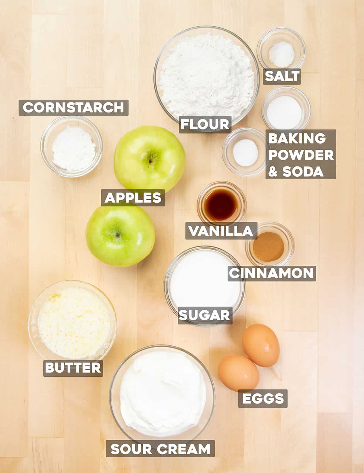 Gluten free apple muffins ingredients in small bowls on light tan wood table