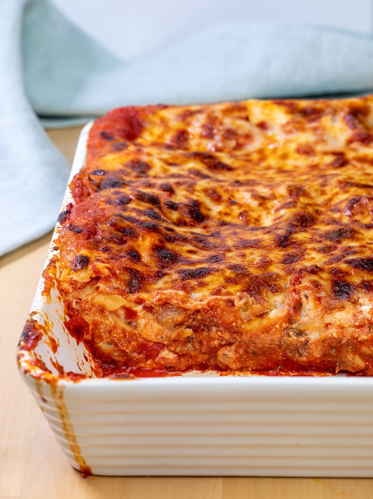 Gluten free lasagna in white casserole dish with some lasagna removed.