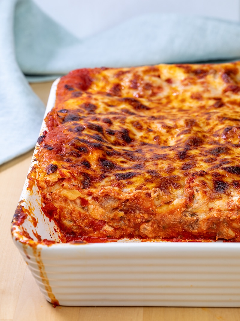 Gluten free lasagna in white casserole dish with some lasagna removed