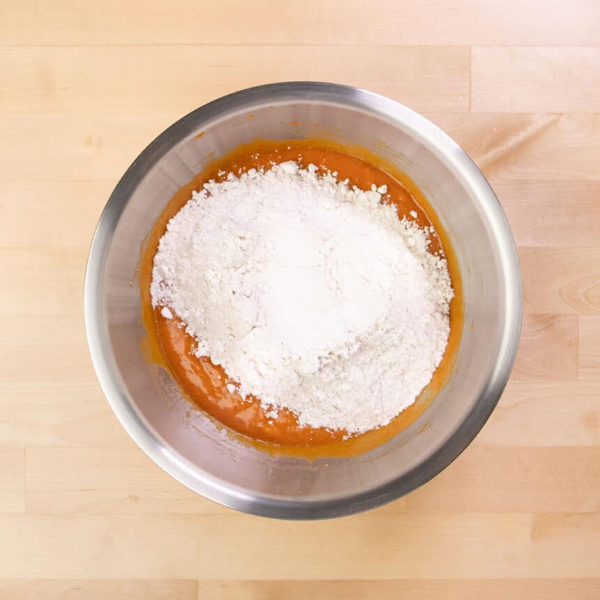 dry powder on top of smooth orange mixture in mixing bowl