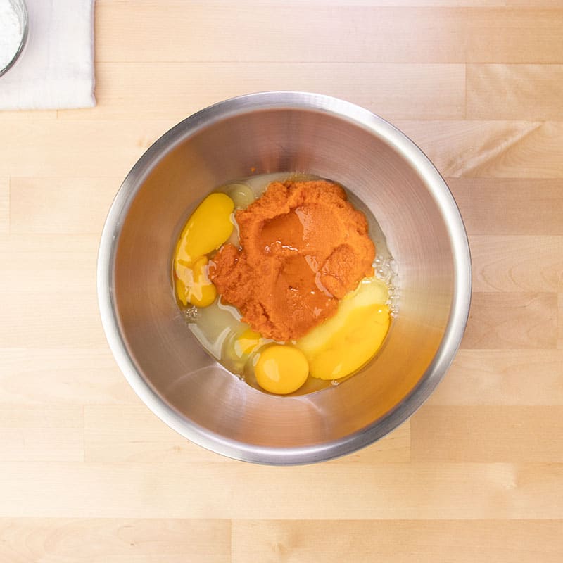 orange pumpkin puree, eggs, and white sugar in large metal mixing bowl