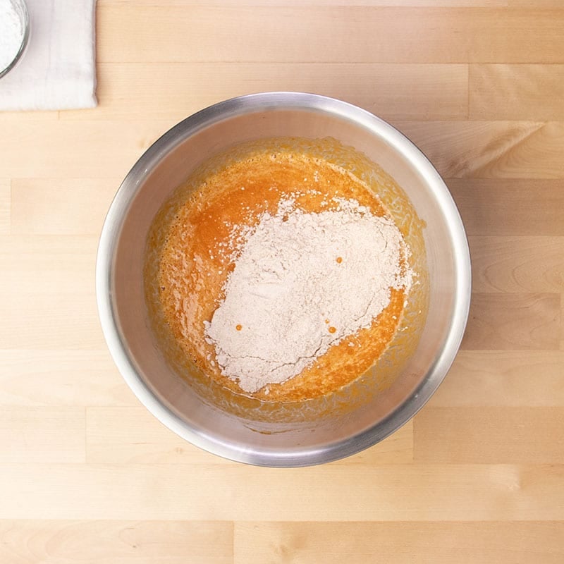 orange wet ingredients with whisked dry ingredients on top in same mixing bowl