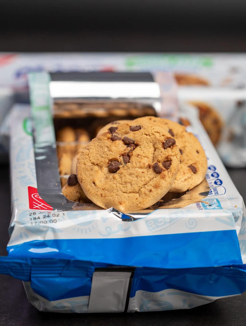 Blue and white Nabisco brand gluten free Chips Ahoy cookie package with some cookies coming out of open package