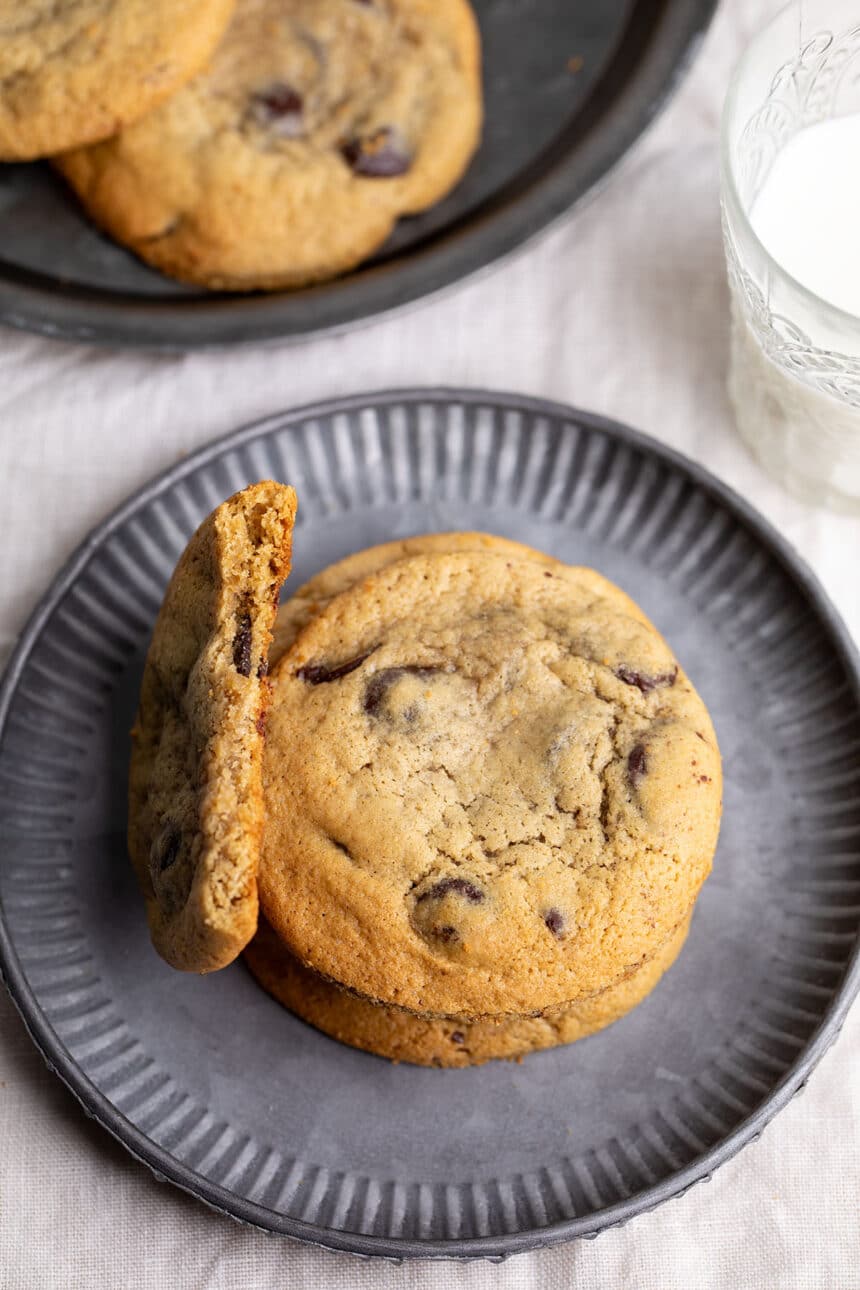 small stack of brown cookies with chocolate chips with one broken cookie showing the chewy inside