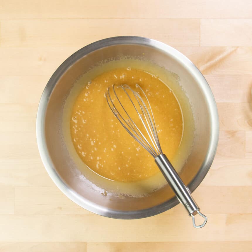 same mixing bowl with ingredients whisked and wire balloon whisk in bowl