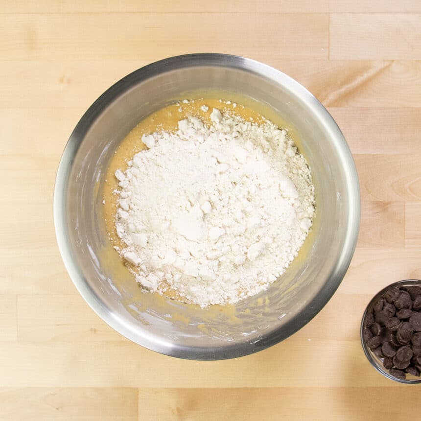 tan oat flour on top of wet ingredients in mixing bowl