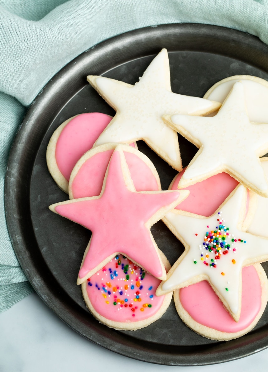 closeup image of star and round shaped light yellow cookies on round dark plate on white surface