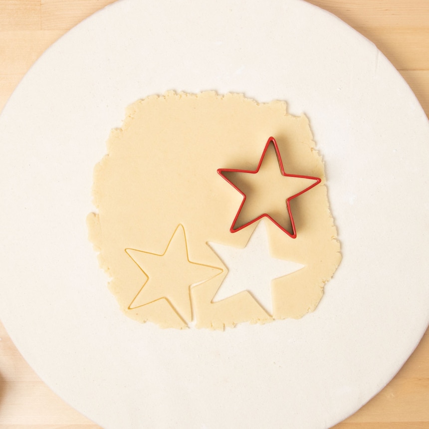 star shaped red cookie cutter cutting shapes in rolled out dough