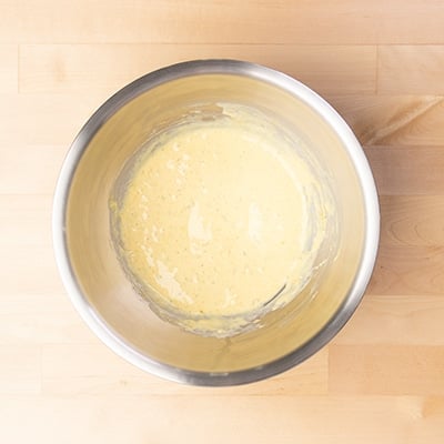 large round metal mixing bowl with light yellow liquid