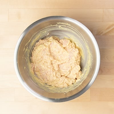 round chicken mixed with yellow mixture in mixing bowl