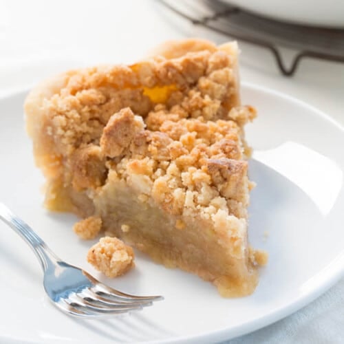 slice of gluten free apple pie with crumble topping on small white plate with metal fork