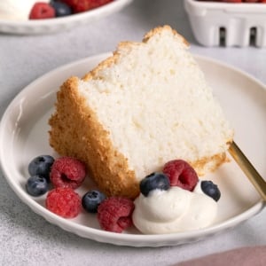 slice of gluten free angel food cake with berries and cream on small white plate