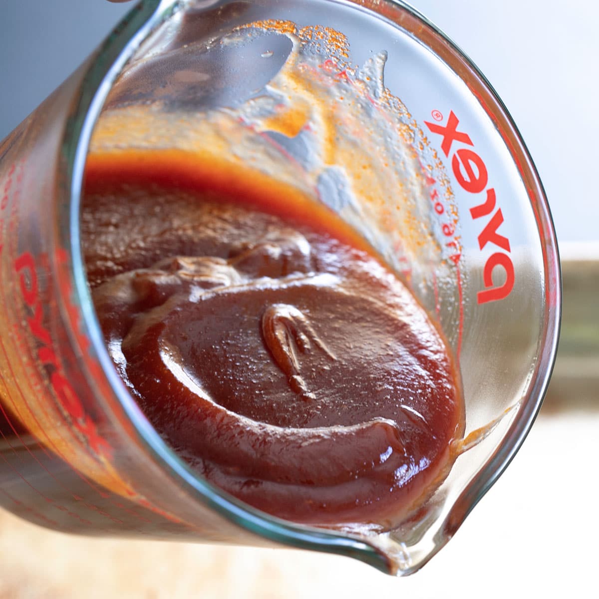 gluten free bbq sauce pouring out of glass measuring cup