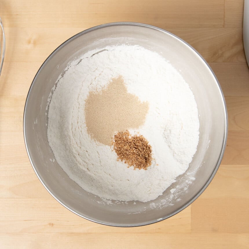 dry ingredients in metal mixing bowl with yeast and ground nutmeg on top