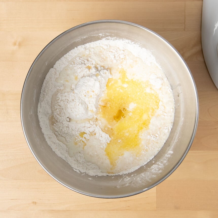 white dry ingredient in round metal mixing bowl with. melted butter, beaten egg, milk