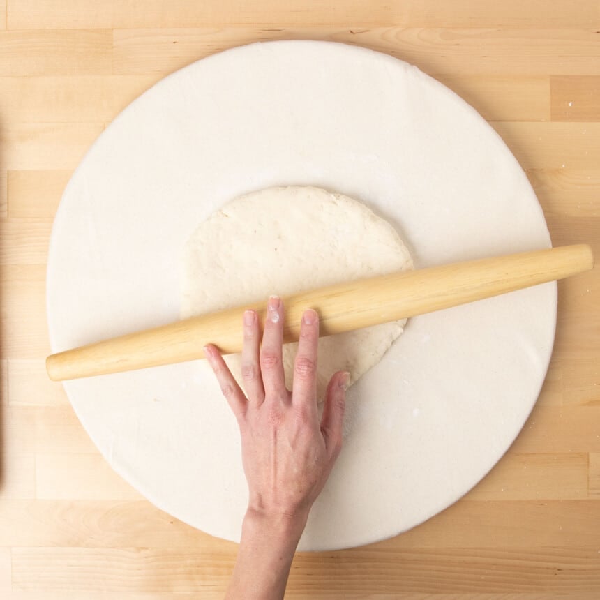 hand using French rolling pin to roll dough into round