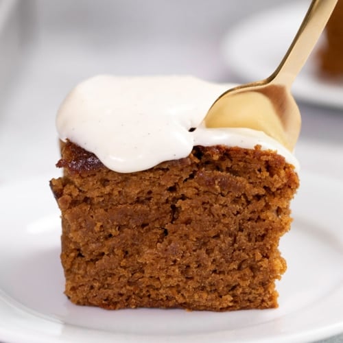 square slice of gluten free gingerbread cake with white icing and fork