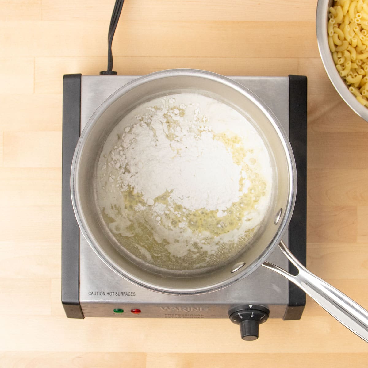 Round metal saucepan with melted butter and unmixed white flour.