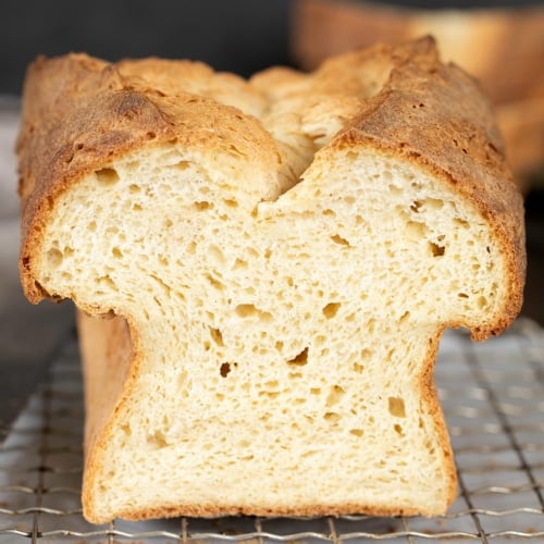 loaf of gluten free rice free bread sliced in half on wire rack