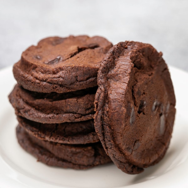 stack of 3 gluten free world peace cookies with one on its side on small white plate