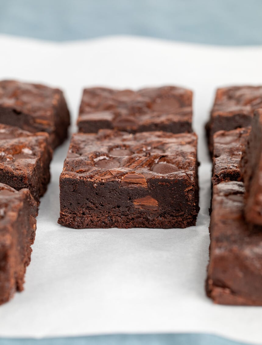 dark brown brownie squares on white paper on blue cloth